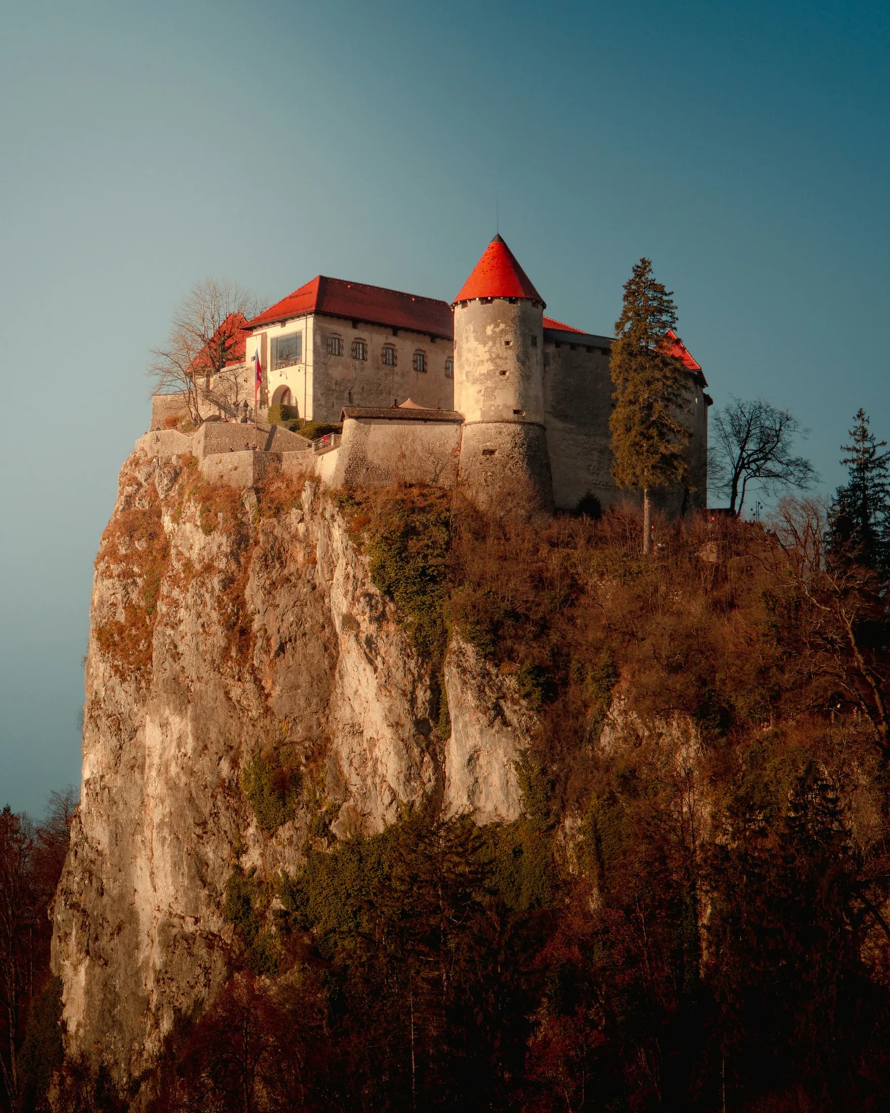 Zgodovinski grad na skalni pečini v topli večerni svetlobi